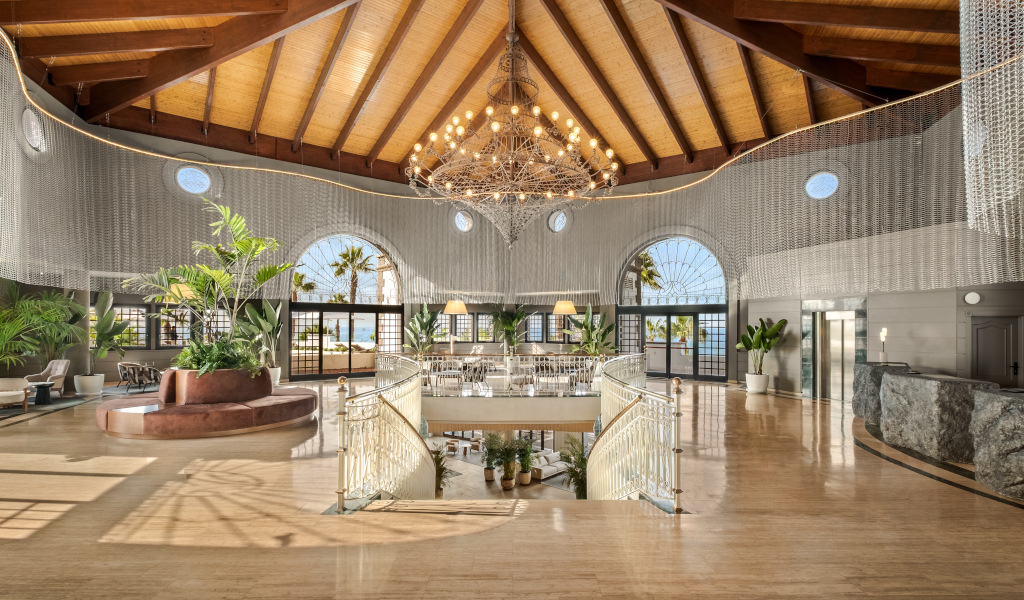 Vestíbulo amplio con techo de madera y plantas en un hotel en Tenerife.