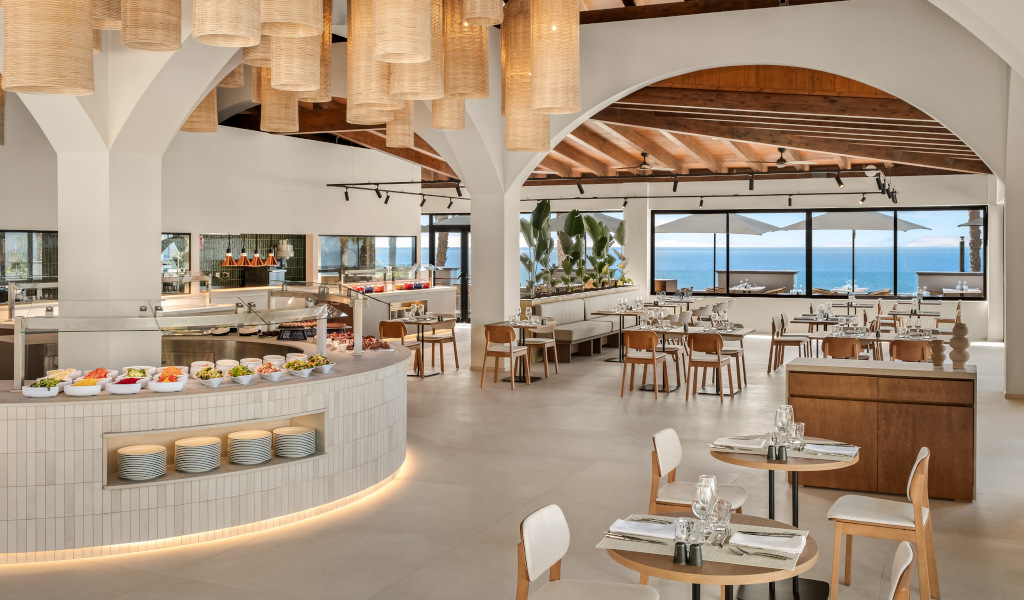 Restaurante con buffet y vista al mar en Tenerife, decoración moderna y mesas dispuestas.