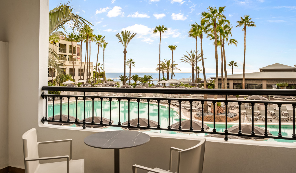 Terraza con vistas a piscina y palmeras en hotel de Tenerife.