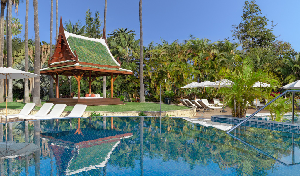 Zona de piscina con tumbonas y quiosco en un jardín tropical en Tenerife.