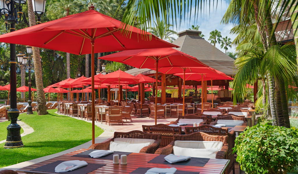 Terraza con sombrillas rojas y mesas en un restaurante al aire libre en Tenerife.