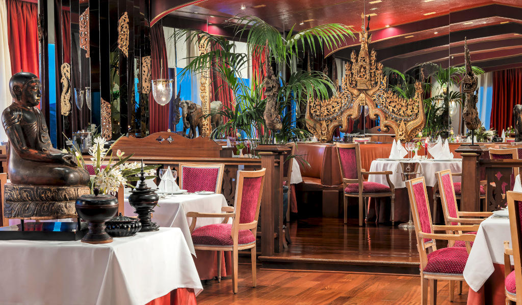 Restaurante decorado con esculturas y plantas en Tenerife, mesas con sillas rojas.