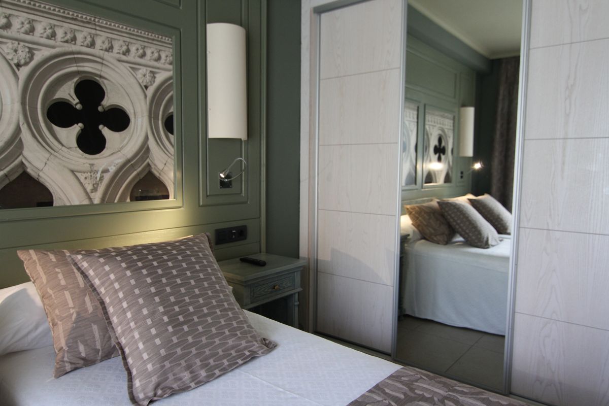 Habitación con espejo reflejando cama y cojines en hotel de Tenerife.