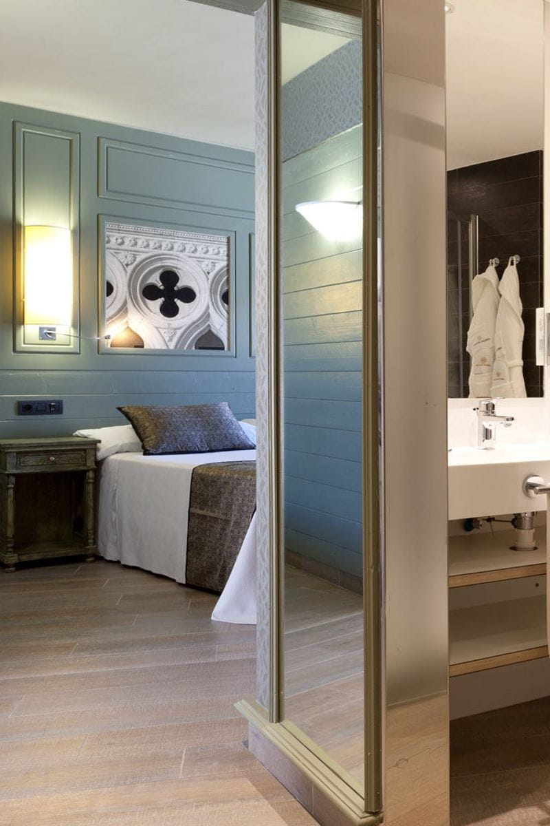 Habitación con cama, mesita y baño en Tenerife. Toallas colgadas junto al lavado.