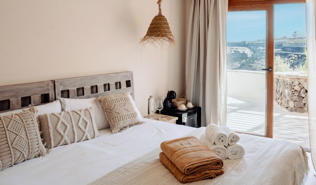 Habitación con cama doble y decoración rústica en alojamiento de Tenerife, vista al exterior.