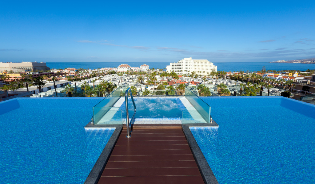 Piscina infinita con vista al mar y edificios en la Costa Adeje, Tenerife.