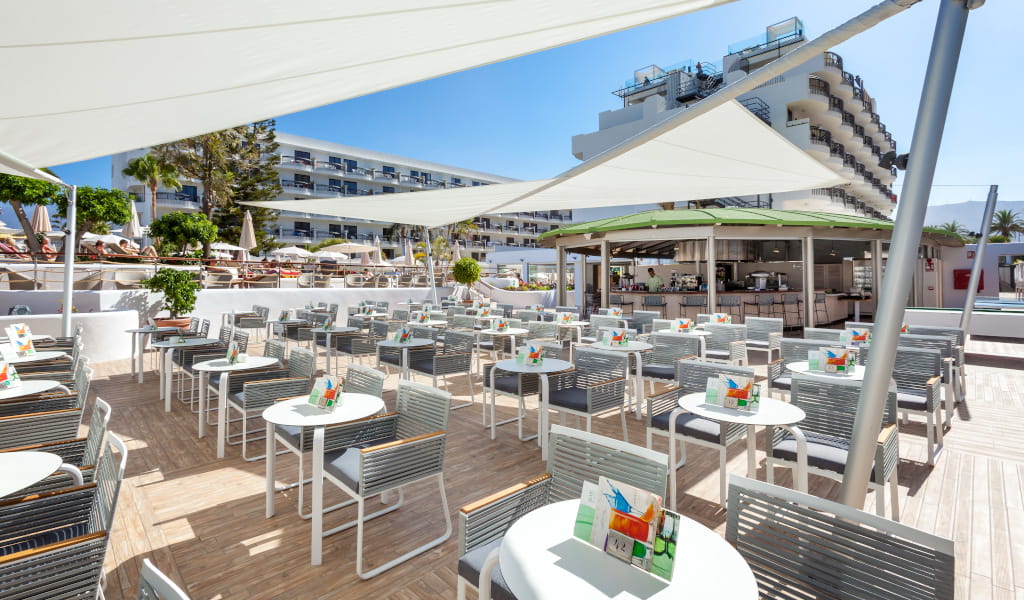Terraza de un restaurante en Tenerife con mesas y sillas al aire libre.