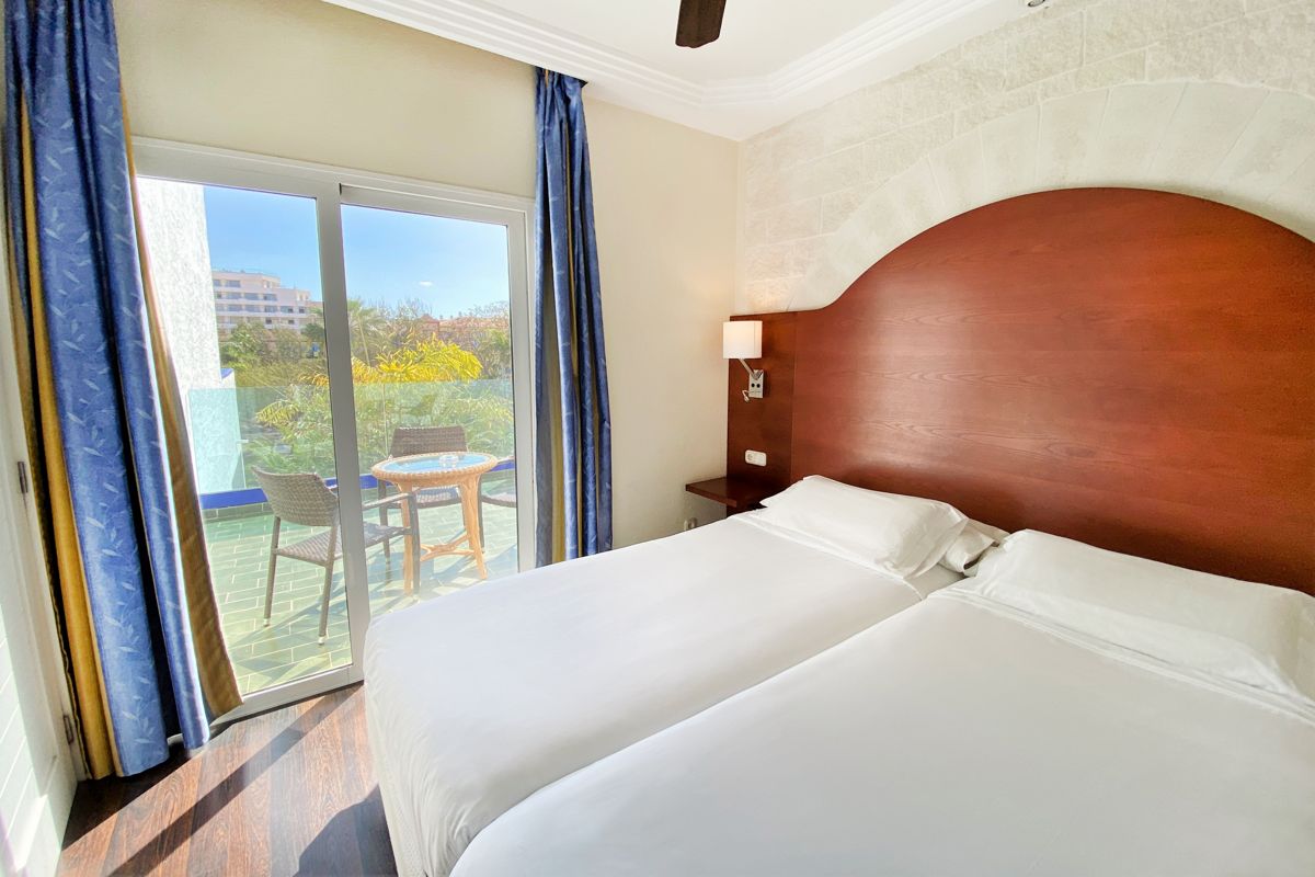 Habitación con dos camas, vista a balcón con sillas y mesa en Tenerife.