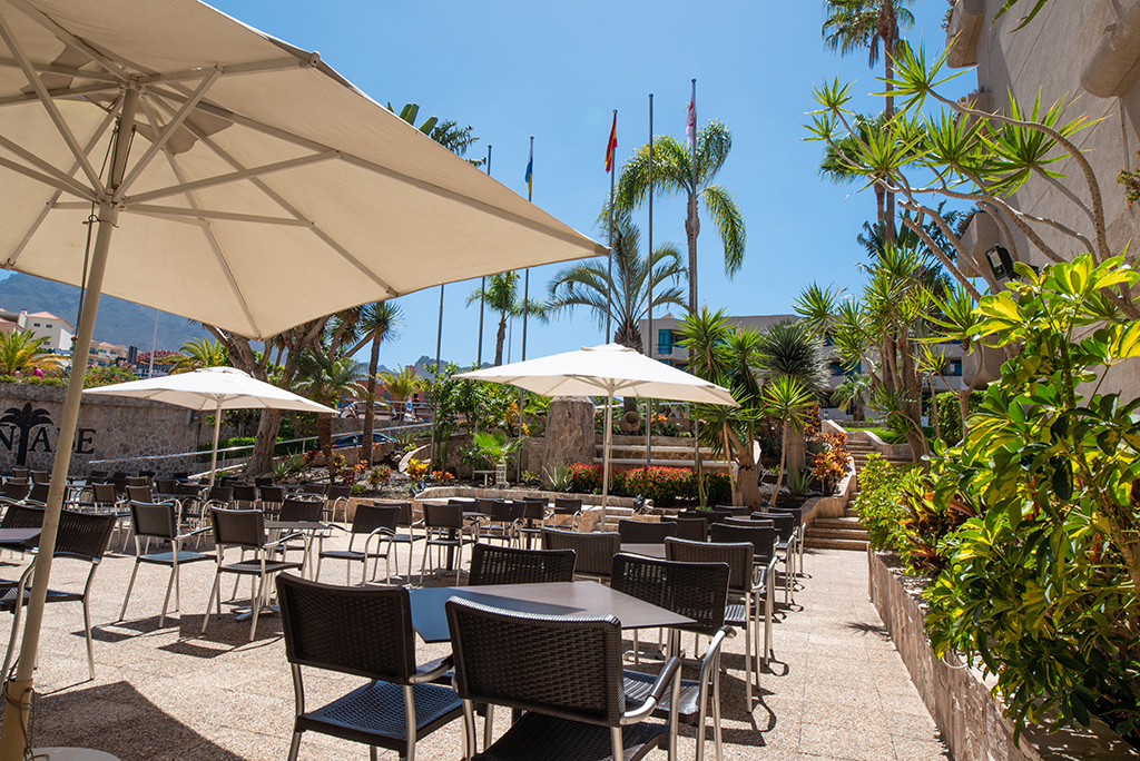 Terraza con mesas y sombrillas rodeada de plantas en un restaurante de Tenerife.