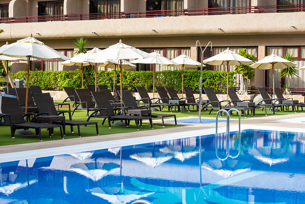 Piscina y tumbonas con sombrillas en un hotel de Tenerife.