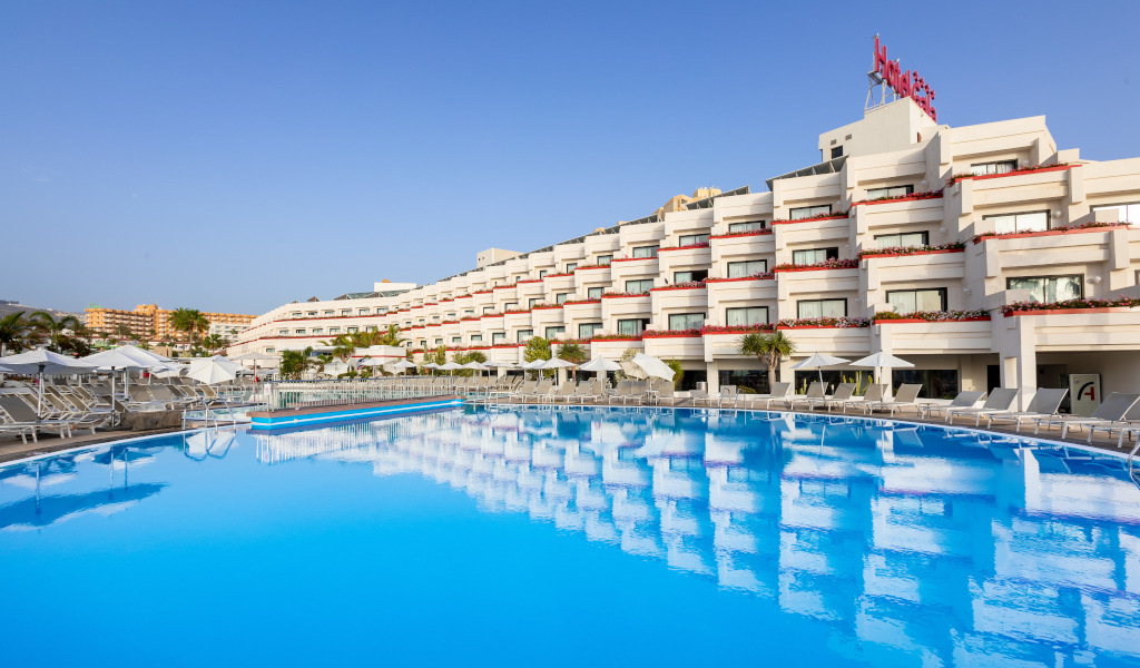 Piscina del hotel en Tenerife con tumbonas y edificio de fondo.