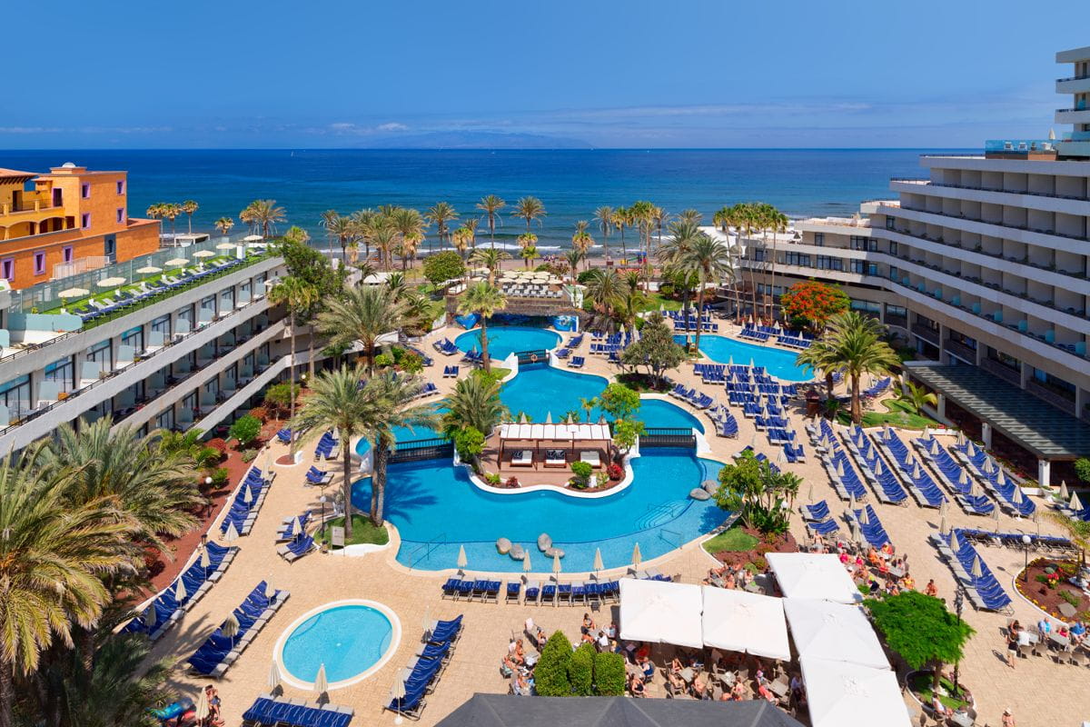 Complejo hotelero con piscinas y tumbonas cerca del mar en Tenerife.