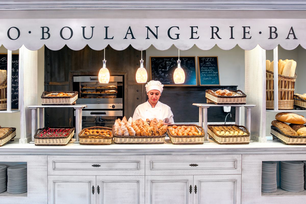 Mujer en panadería con bandejas de pan y pasteles en Tenerife.