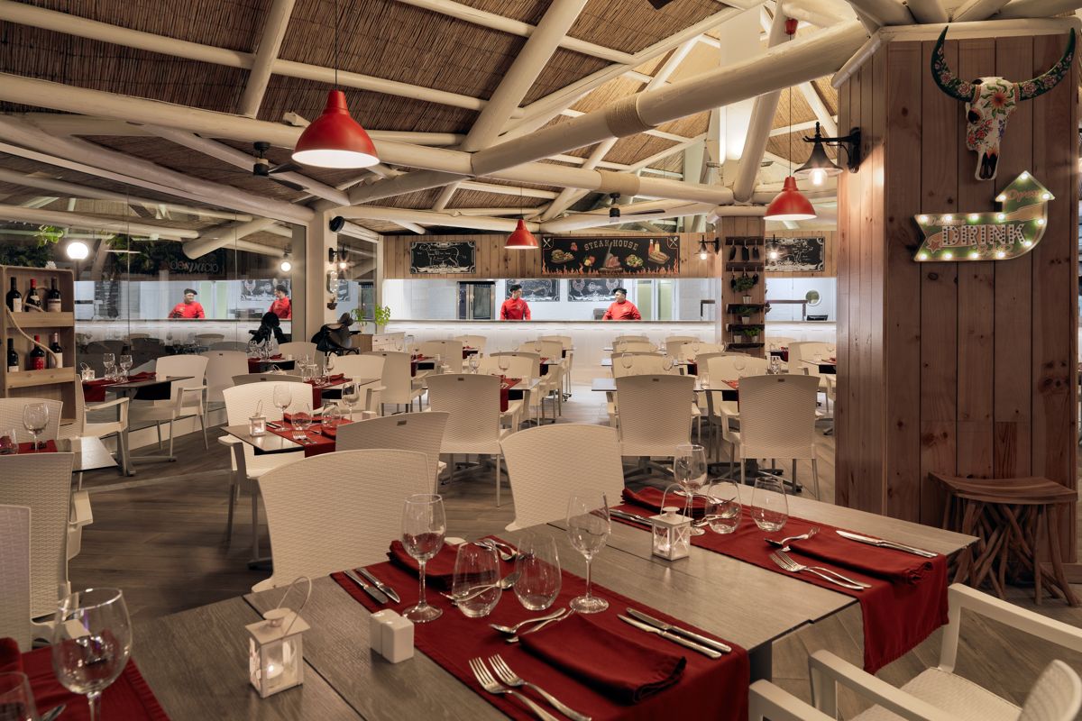 Restaurante en Tenerife con mesas decoradas y chefs al fondo en cocina abierta.