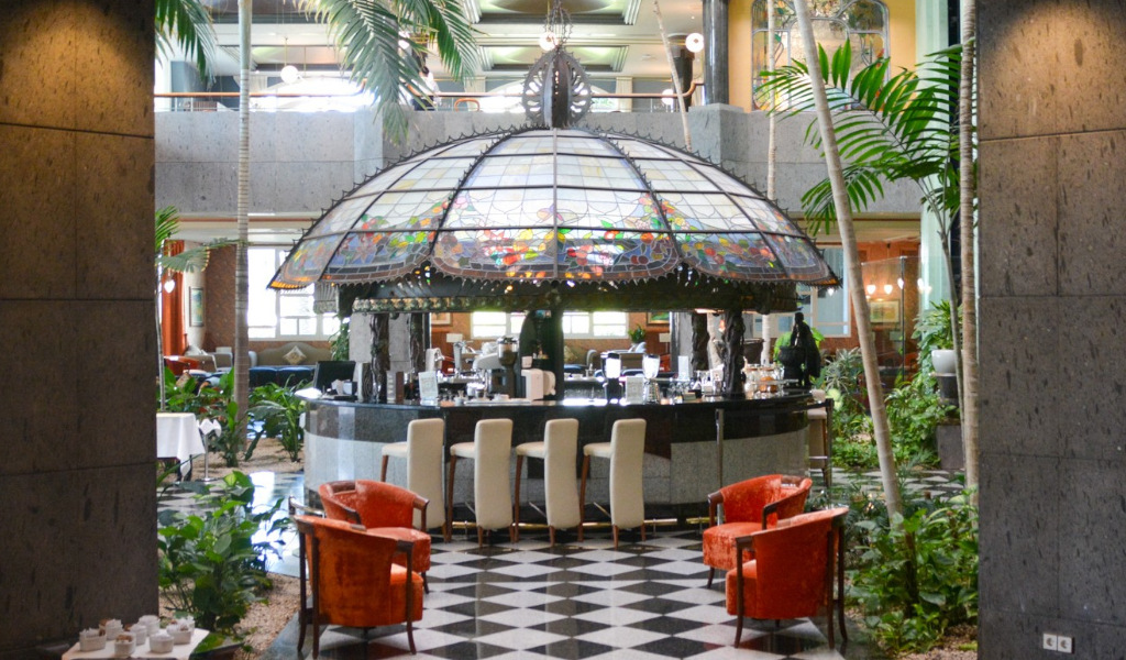 Bar en un hotel de Tenerife con cúpula de vitral y sillas alrededor.