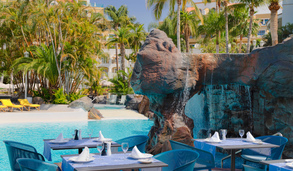 Mesa preparada junto a cascada y piscina en hotel de Tenerife.