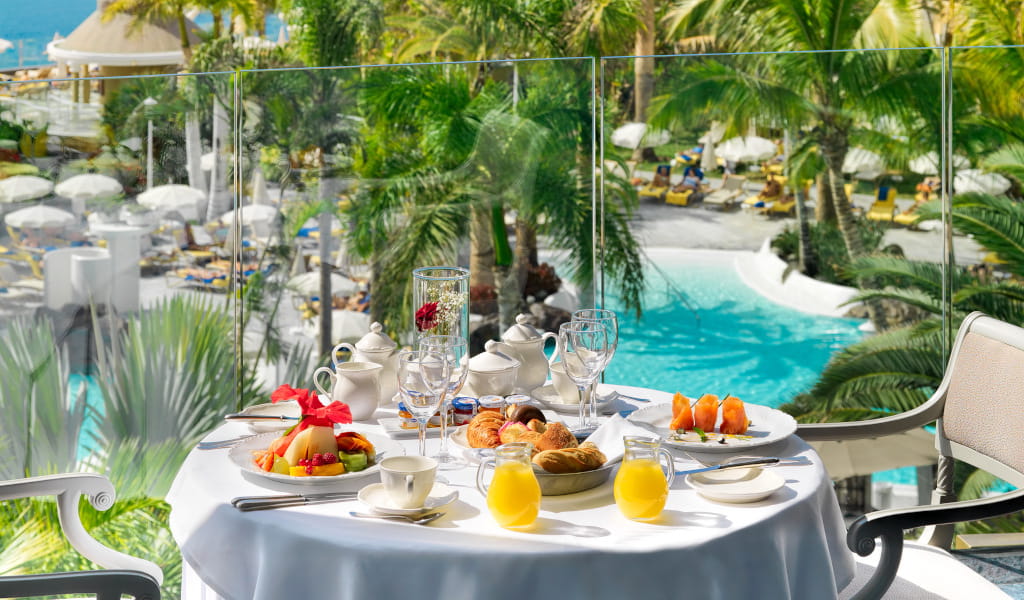Desayuno servido en una terraza con vista a la piscina en Tenerife.