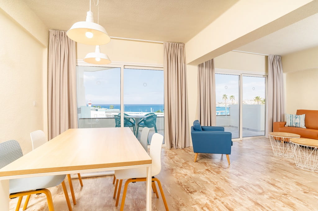 Sala de estar con vista al mar en Tenerife, con mesa de comedor y sillones.