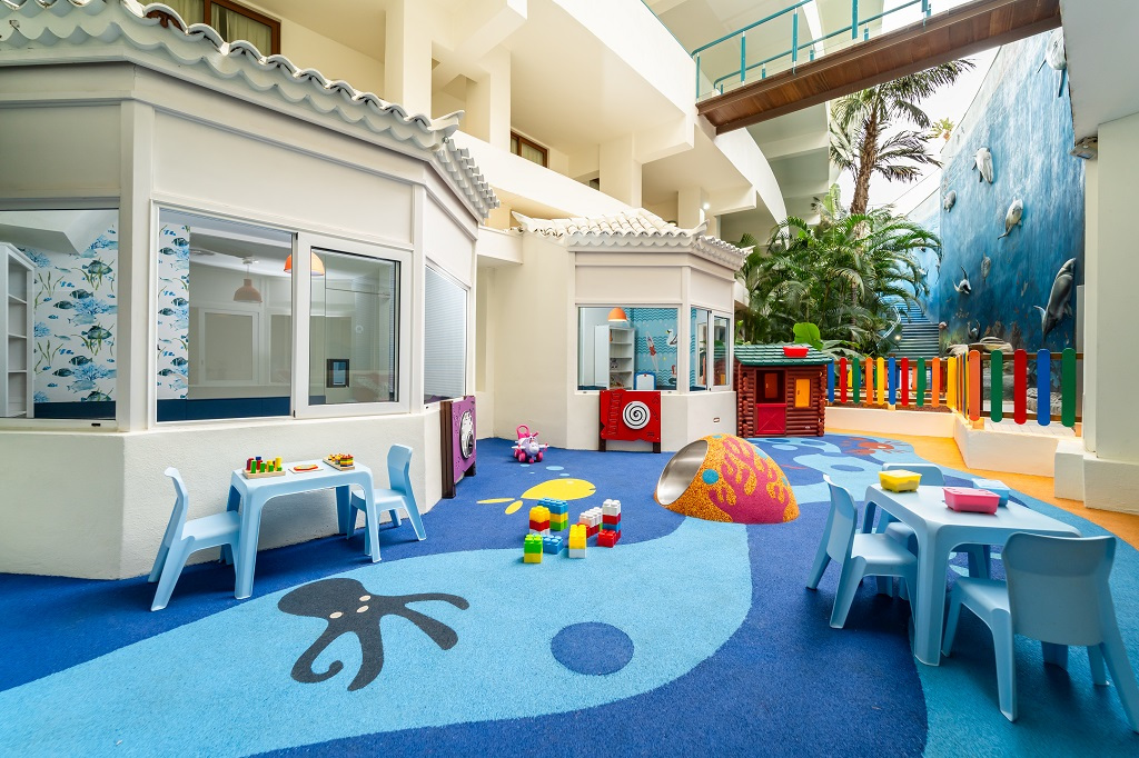 Área de juegos infantiles con mesas, sillas y juguetes en un espacio colorido en Tenerife.