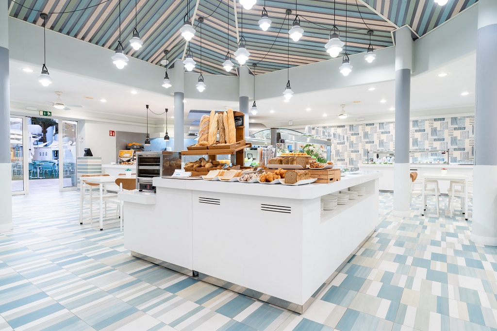 Interior de cafetería en Tenerife con estantes llenos de panes y productos horneados.