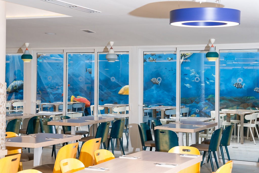Comedor con mural oceánico y sillas de colores en un restaurante de Tenerife.