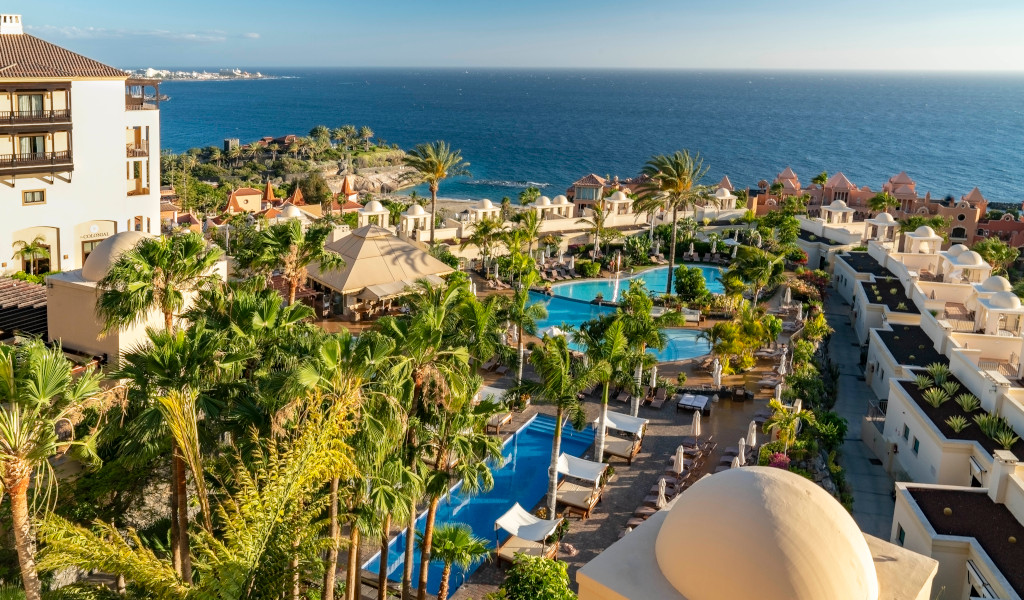 Vista aérea de complejo turístico en Costa Adeje, Tenerife, con piscinas y mar al fondo.