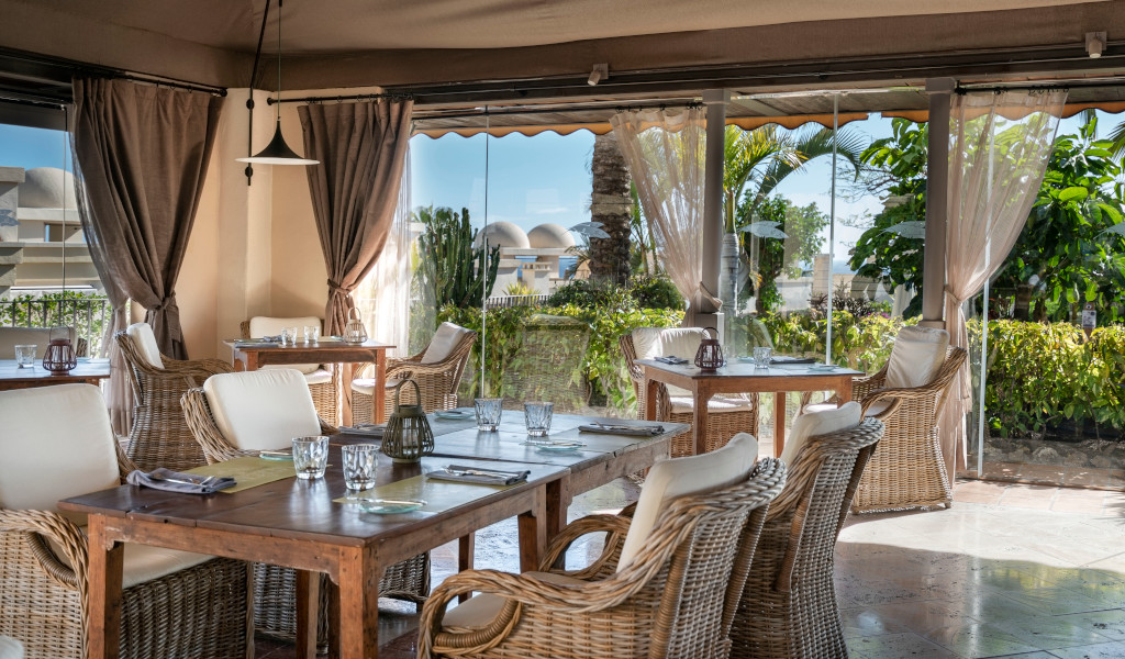 Restaurante con mesas y sillas de mimbre, vistas al jardín en Tenerife.