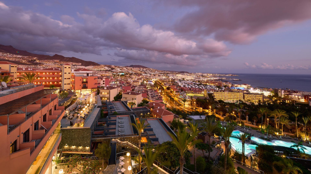 Vista nocturna de la costa de Tenerife con edificios iluminados y el mar al fondo.