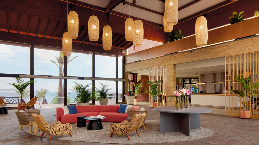 Lobby iluminado con lámparas colgantes y sofás en hotel de Tenerife.