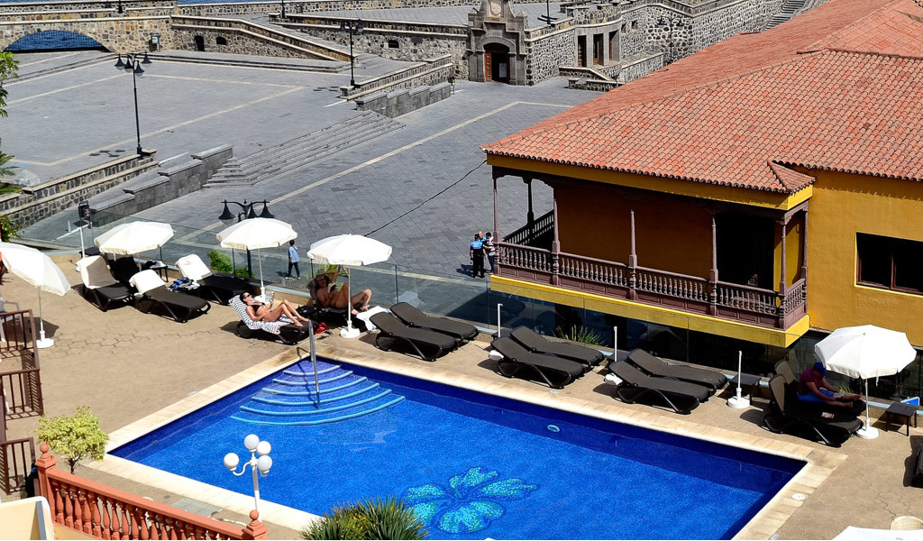 Piscina al aire libre con sombrillas y tumbonas en una plaza de Tenerife.