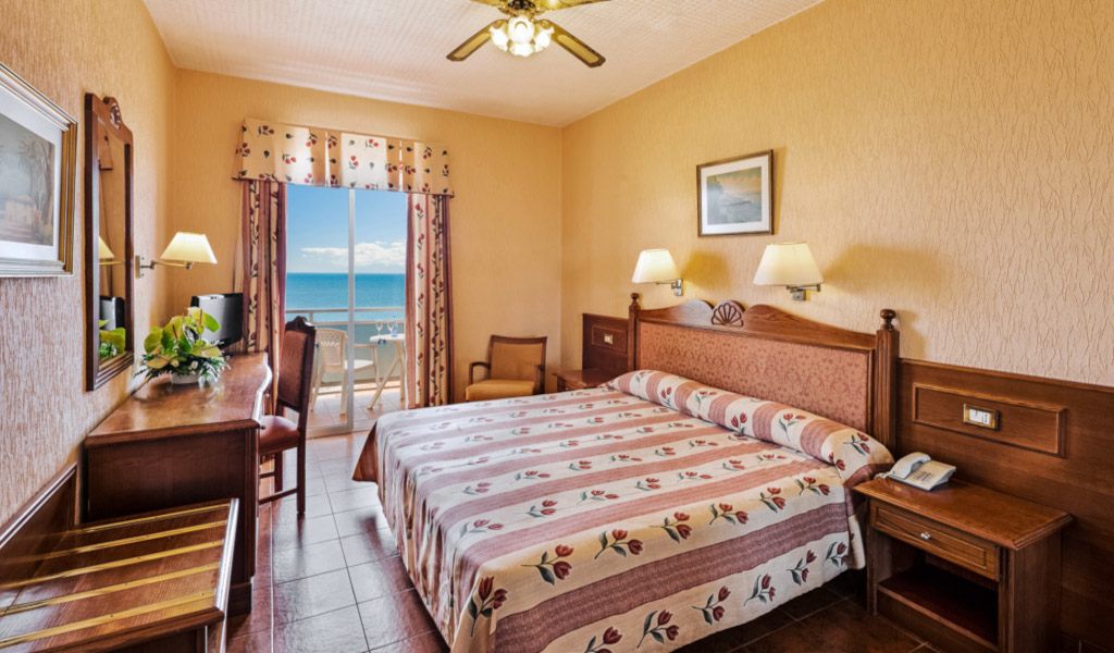 Habitación de hotel en Tenerife con cama doble y vista al mar desde el balcón.