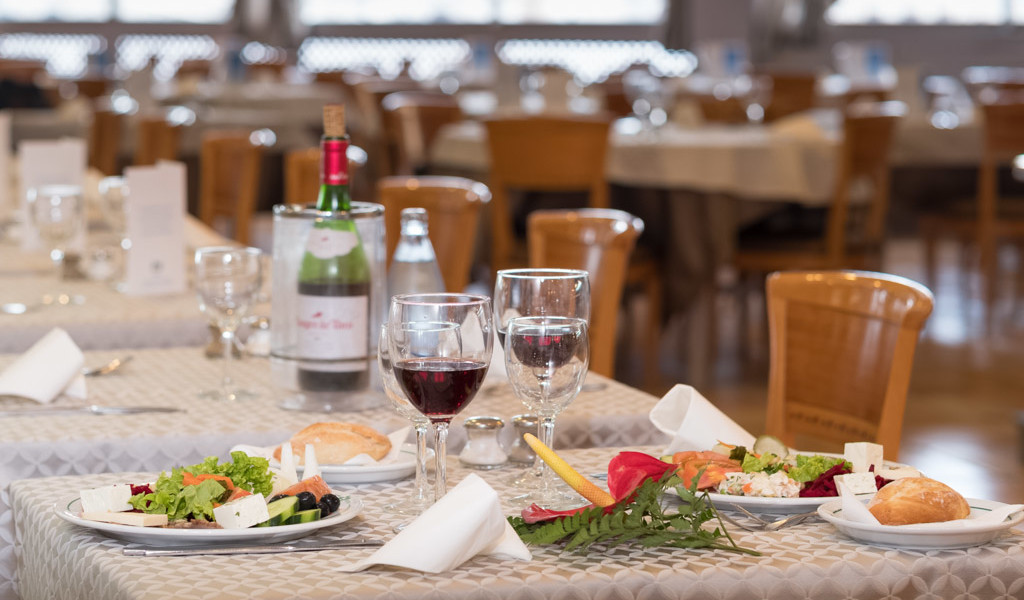 Mesa servida con ensaladas, pan, copas de vino tinto y una botella en un restaurante de Tenerife.