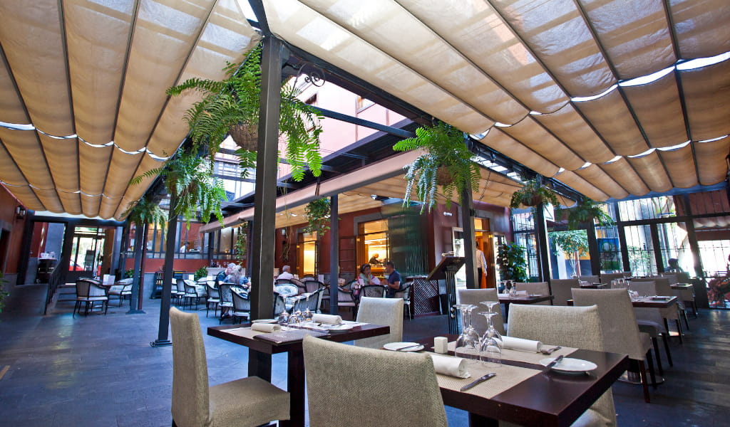 Restaurante al aire libre en Tenerife con mesas y plantas colgantes.