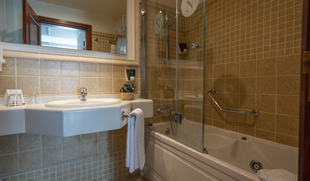 Baño en suite con lavabo, bañera y alicatado beige en Tenerife.