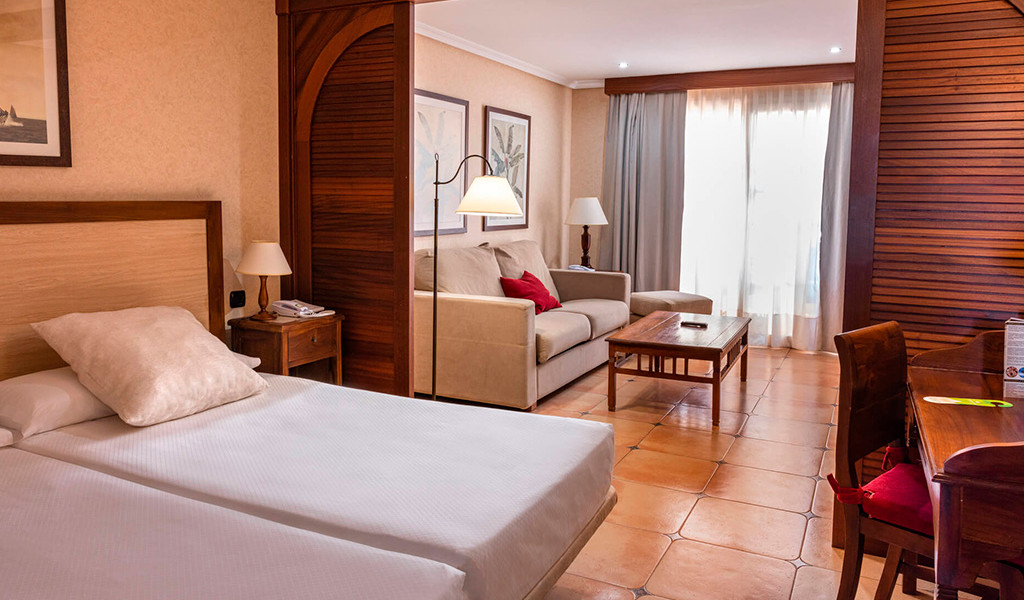 Habitación de hotel en Tenerife con cama, sofá y mesa de centro.