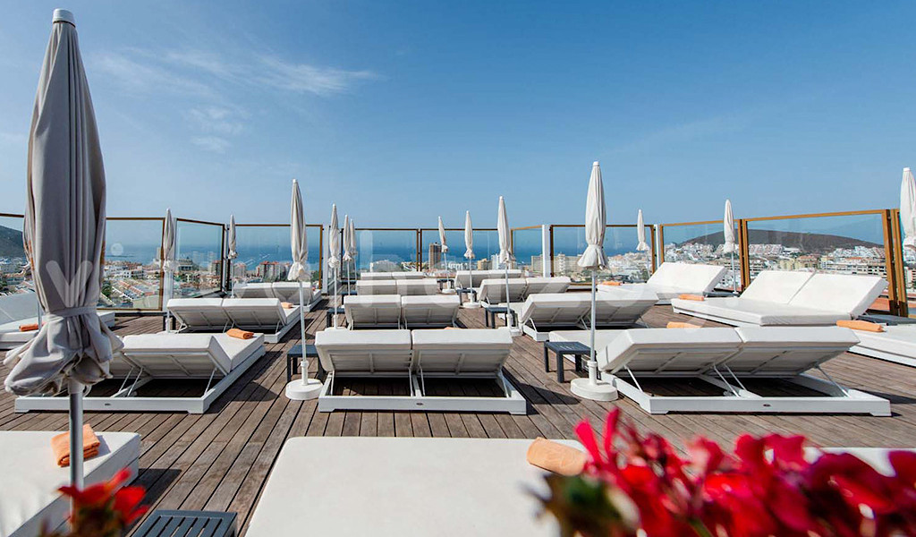 Tumbonas blancas con sombrillas en una terraza con vista al mar en Tenerife.