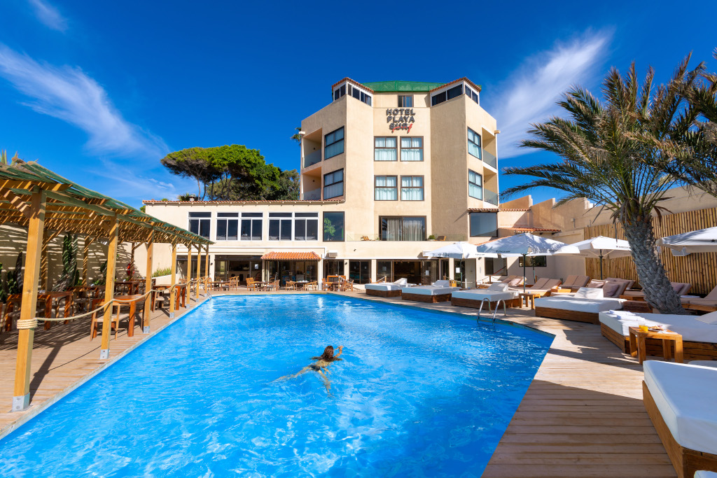Piscina al aire libre del Hotel El Dorado en Tenerife con tumbonas y palmeras.