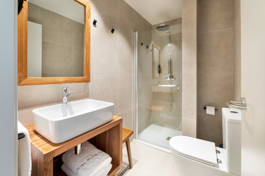 Baño moderno con lavabo, espejo y ducha en hotel de Tenerife.