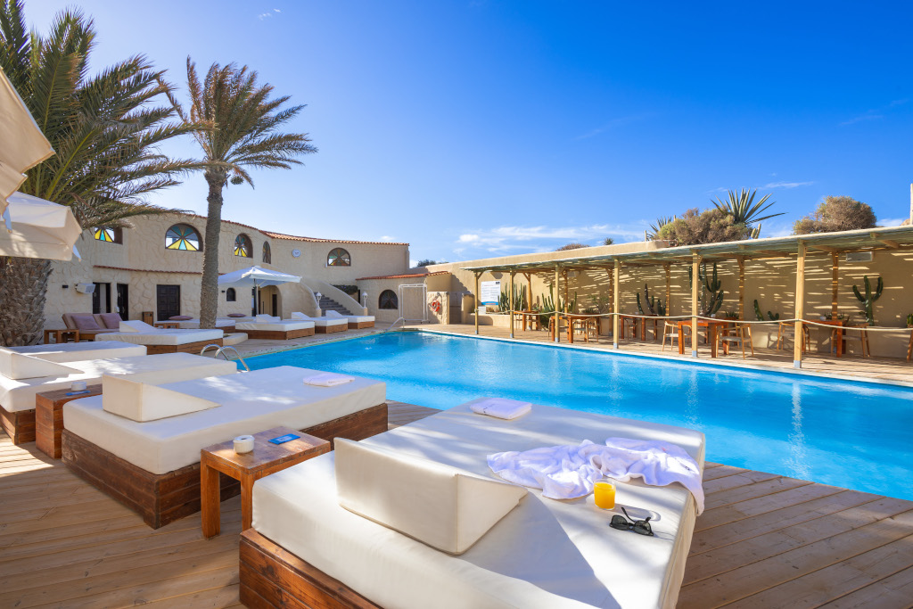 Piscina rodeada de camas balinesas y palmeras en Tenerife.