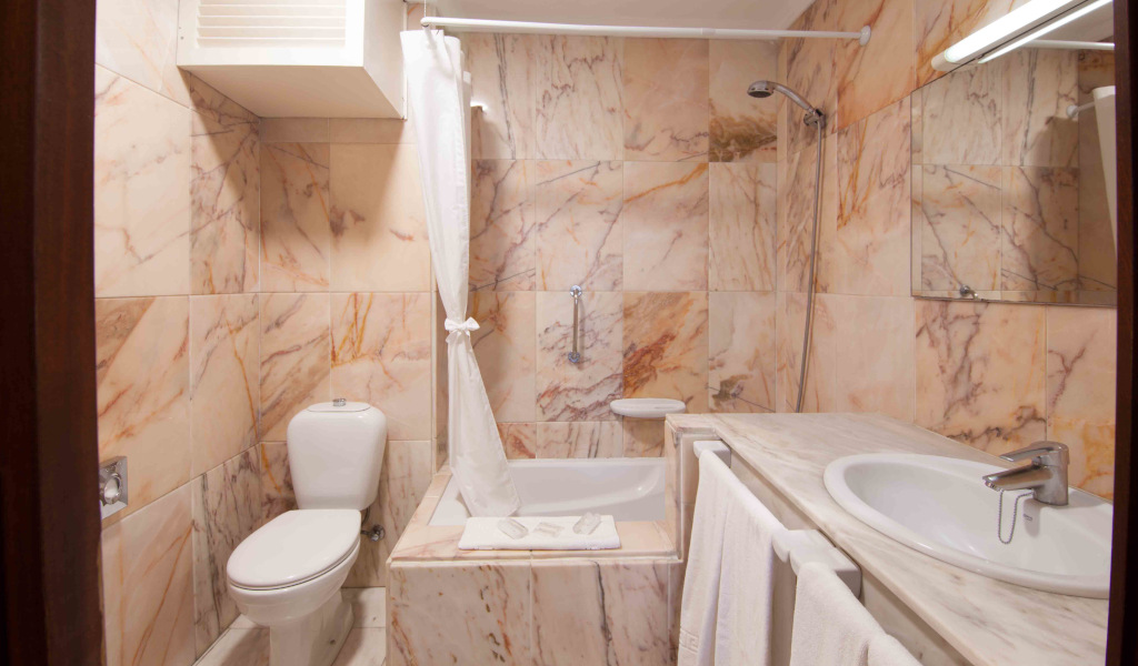 Baño de mármol con inodoro, bañera y lavabo en Tenerife.