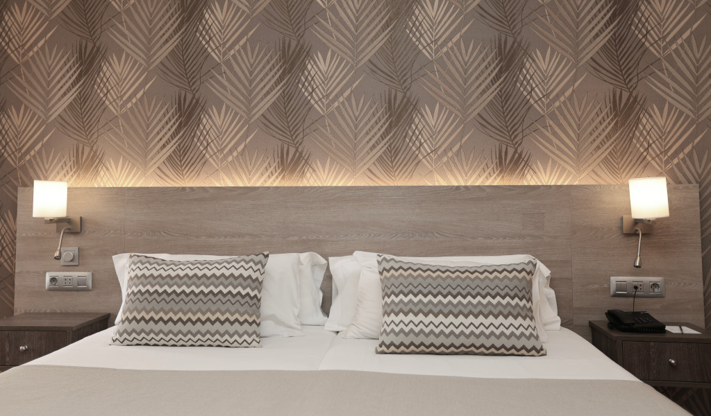 Cama doble con cabecera de madera y lámparas de pared en habitación de hotel en Tenerife.