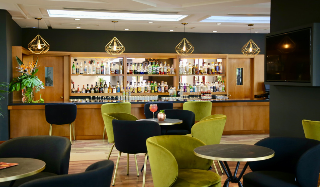 Bar con estantería de licores y mesas verdes y negras, Tenerife.