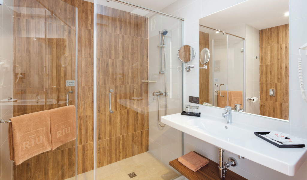 Baño del hotel en Tenerife con ducha y lavabo. Toallas colgadas, marca Riu.