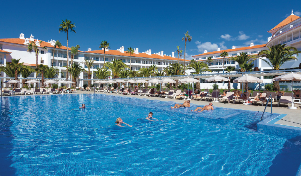 Piscina al aire libre con personas nadando frente a un hotel en Tenerife.