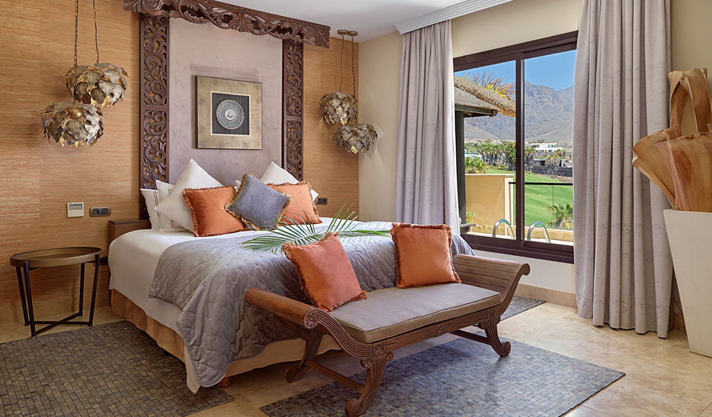 Habitación con cama, cojines naranjas, ventana con vista al paisaje en Adeje, Tenerife.