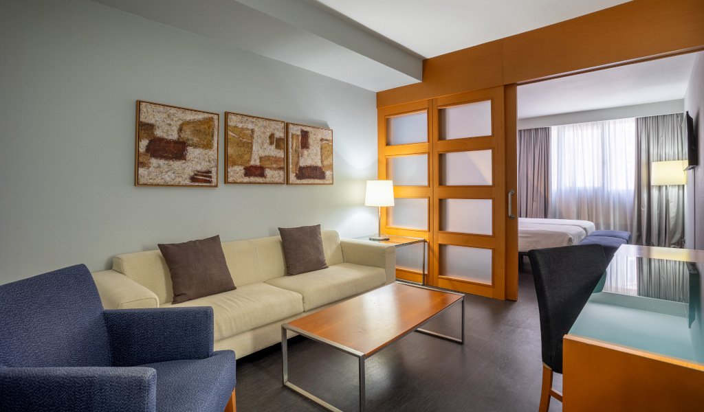 Sala de estar de hotel en Tenerife con sofá, mesa, lámpara y puerta corrediza.