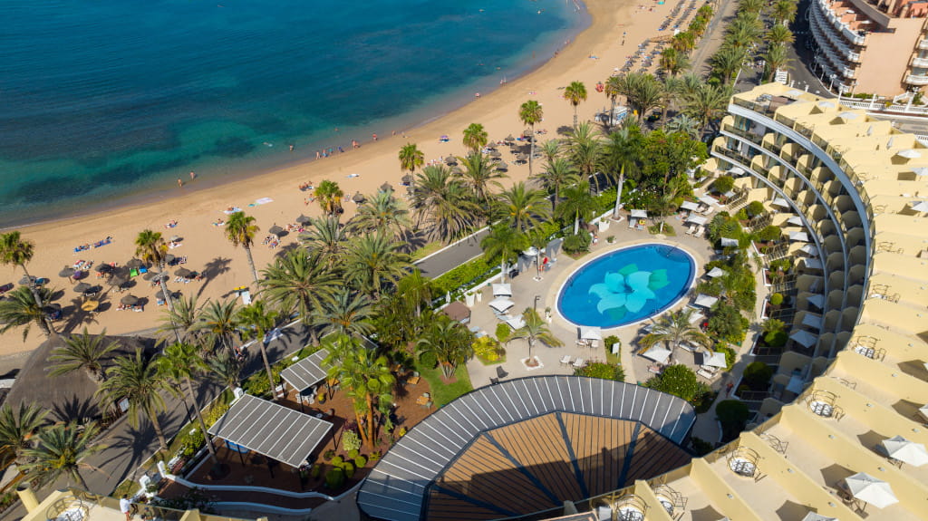 Playa con palmeras y piscina en un hotel de Tenerife, vista aérea.