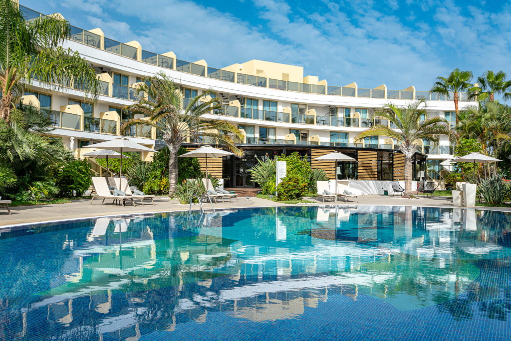 Piscina del hotel rodeada de palmeras y tumbonas en Tenerife.