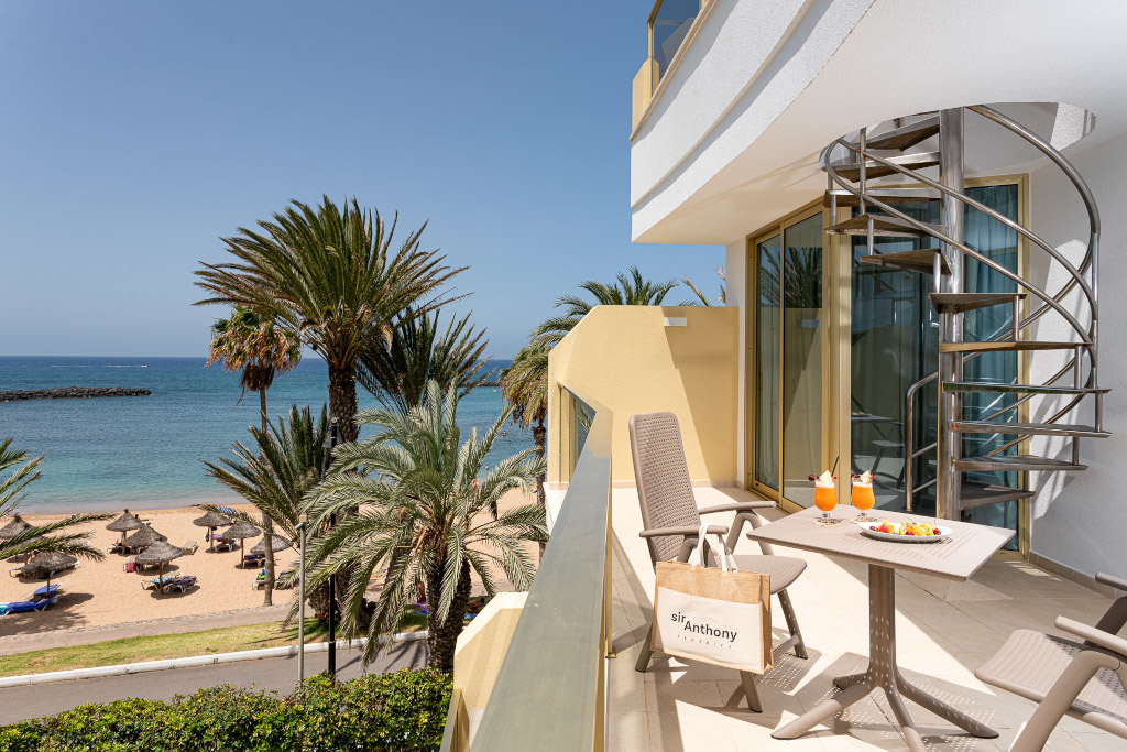 Balcón con sillas, mesa con bebidas y vista al mar en Tenerife.