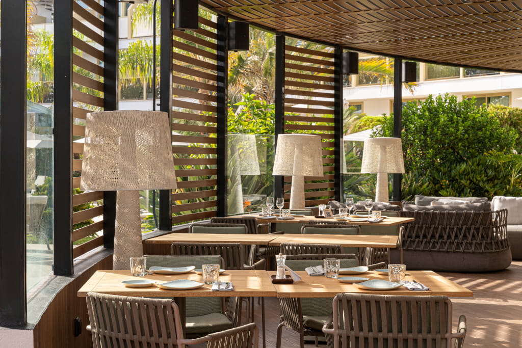 Terraza con mesas y sillas rodeadas de plantas en un restaurante en Tenerife.